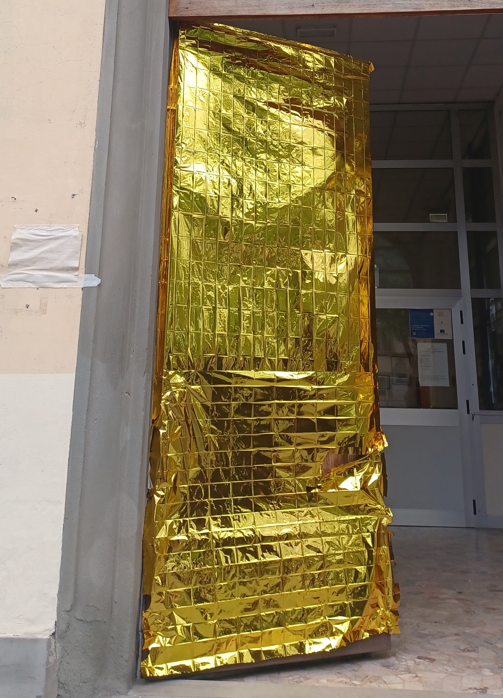 Coperte termiche metalline sulla porta della scuola elementare Villani, Firenze, aprile 2025 Coperte termiche metalline sulla porta della scuola elementare Villani, Firenze, aprile 2025